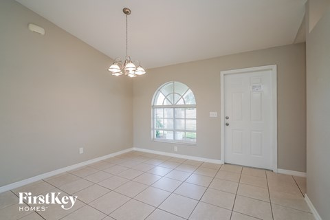 an empty dining room with a white door and a window