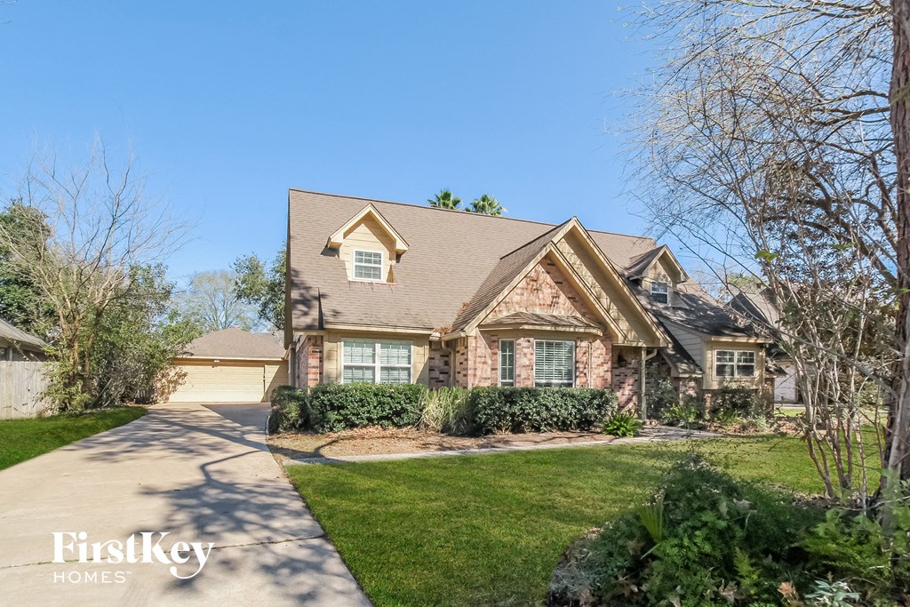 two story home with brick exterior and green grass and trees