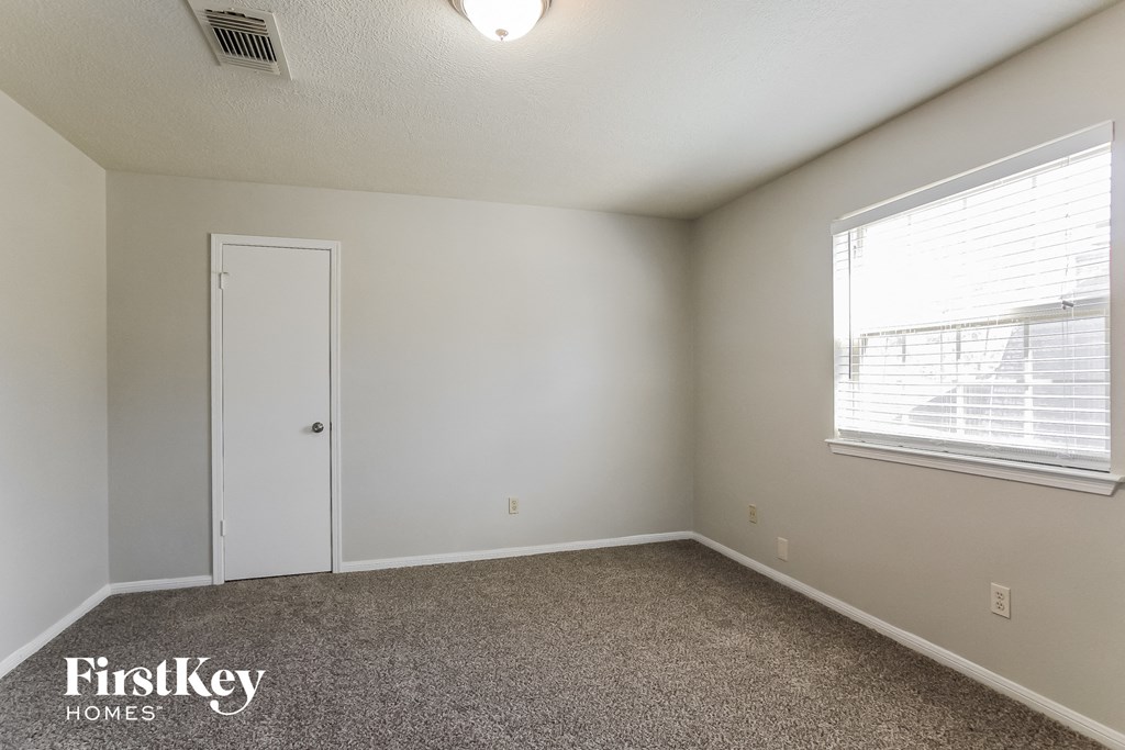the living room of an apartment with carpet and a window