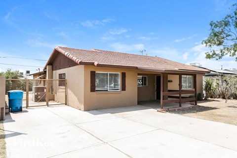 a small tan house with a patio and a fence