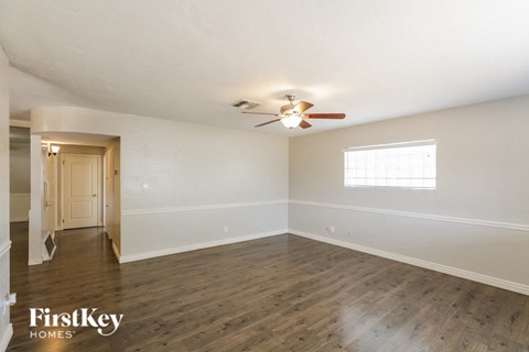 an empty living room with white walls and a ceiling fan
