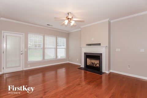 A spacious living room with a fireplace and a ceiling fan.