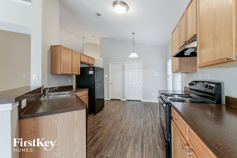 A kitchen with wooden cabinets and a black fridge.