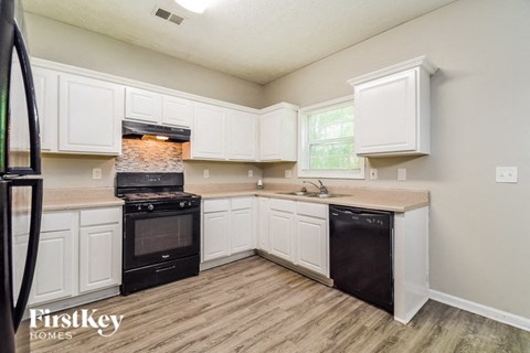 A kitchen with a black stove top oven and a black dishwasher.