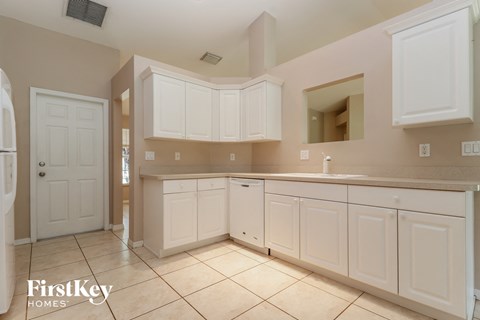 A kitchen with white cabinets and a tiled floor.
