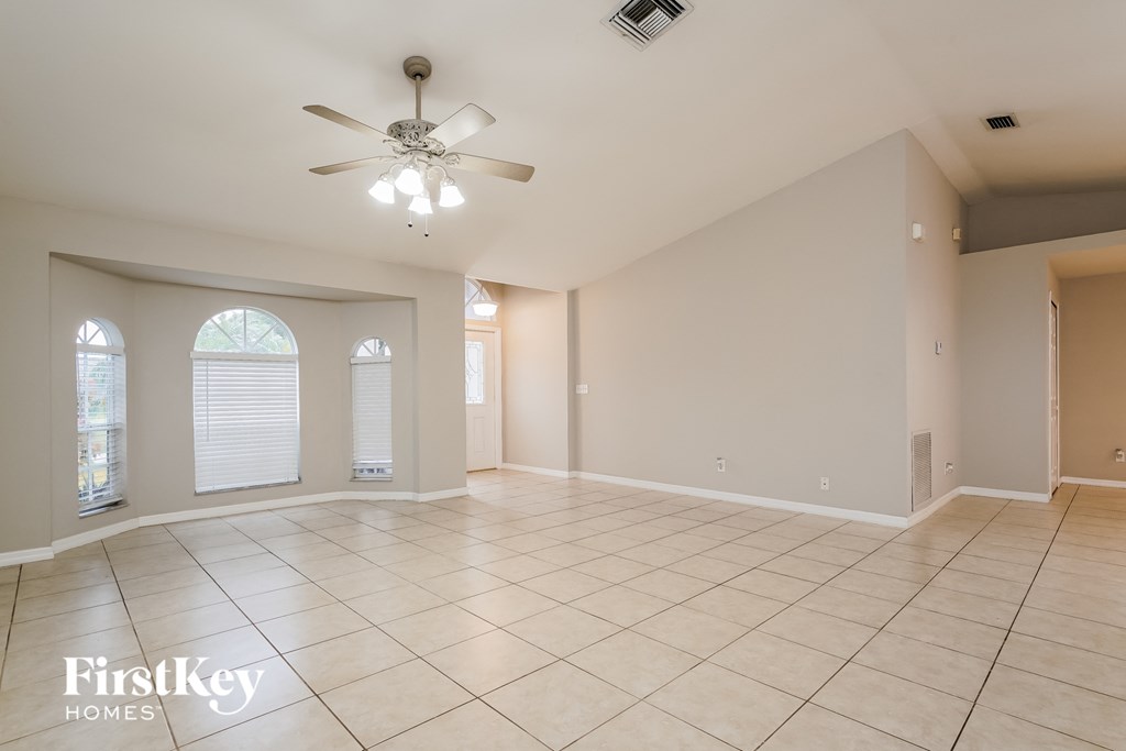 a spacious living room with tile flooring and a ceiling fan