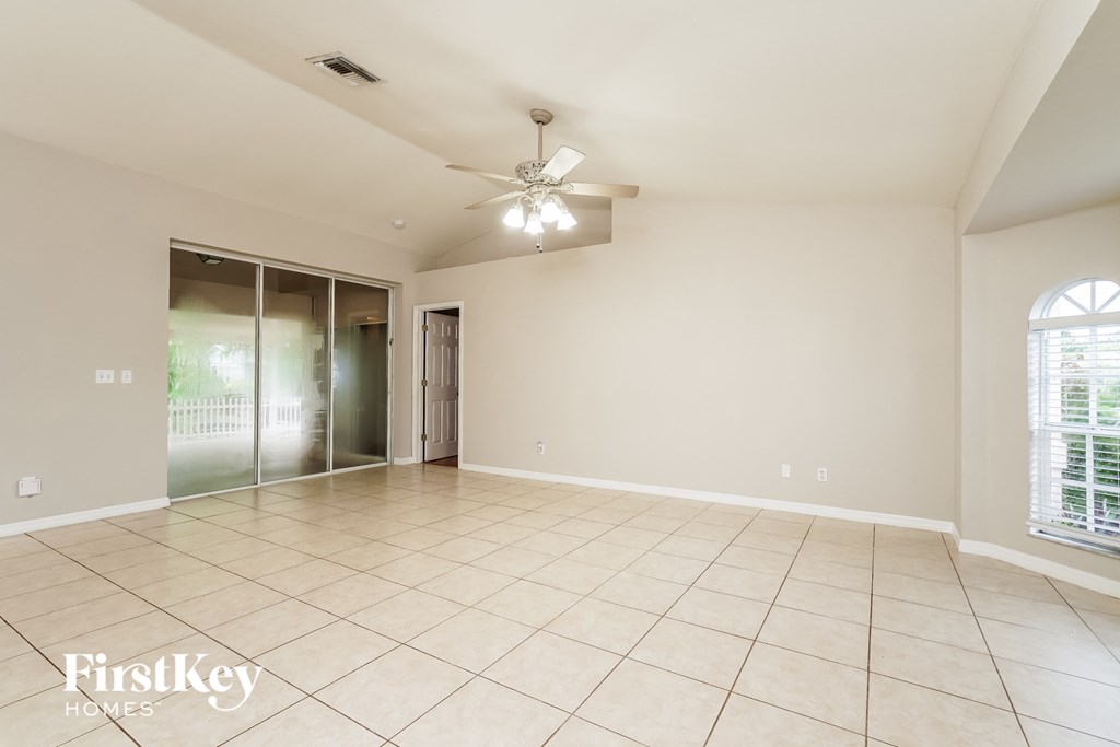 an empty living room with a ceiling fan and tile flooring