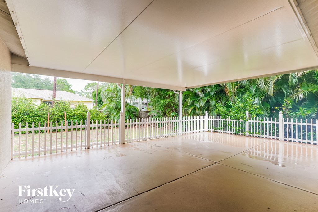 a large porch with a white fence and a view of trees
