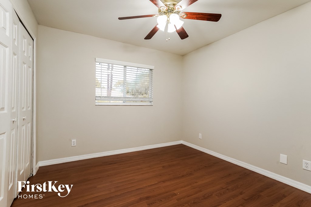a bedroom with hardwood flooring and a ceiling fan