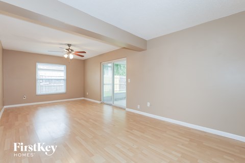 A spacious room with wooden flooring and a ceiling fan.
