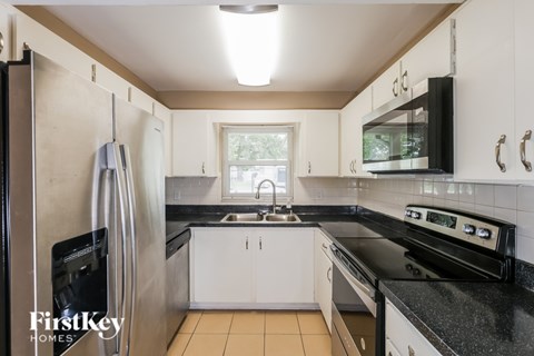 A kitchen with a black stove top oven and a black microwave above it.