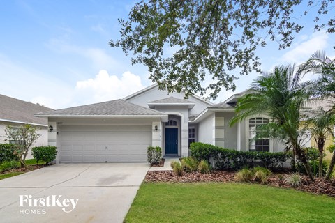 a white house with a driveway and a palm tree