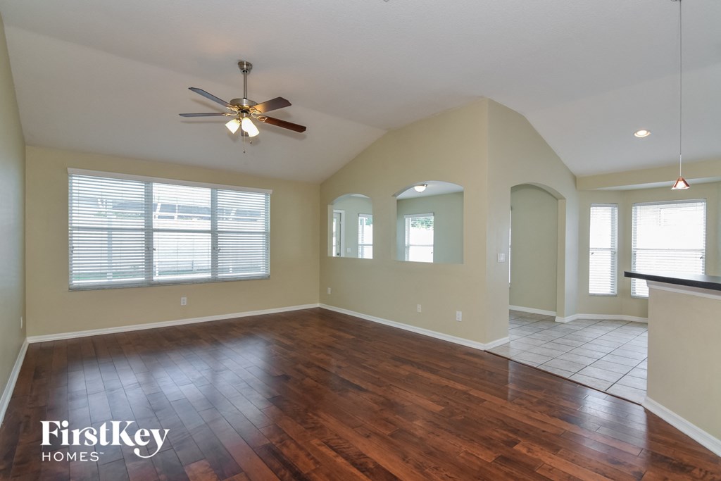 an empty living room with wood floors and a ceiling fan