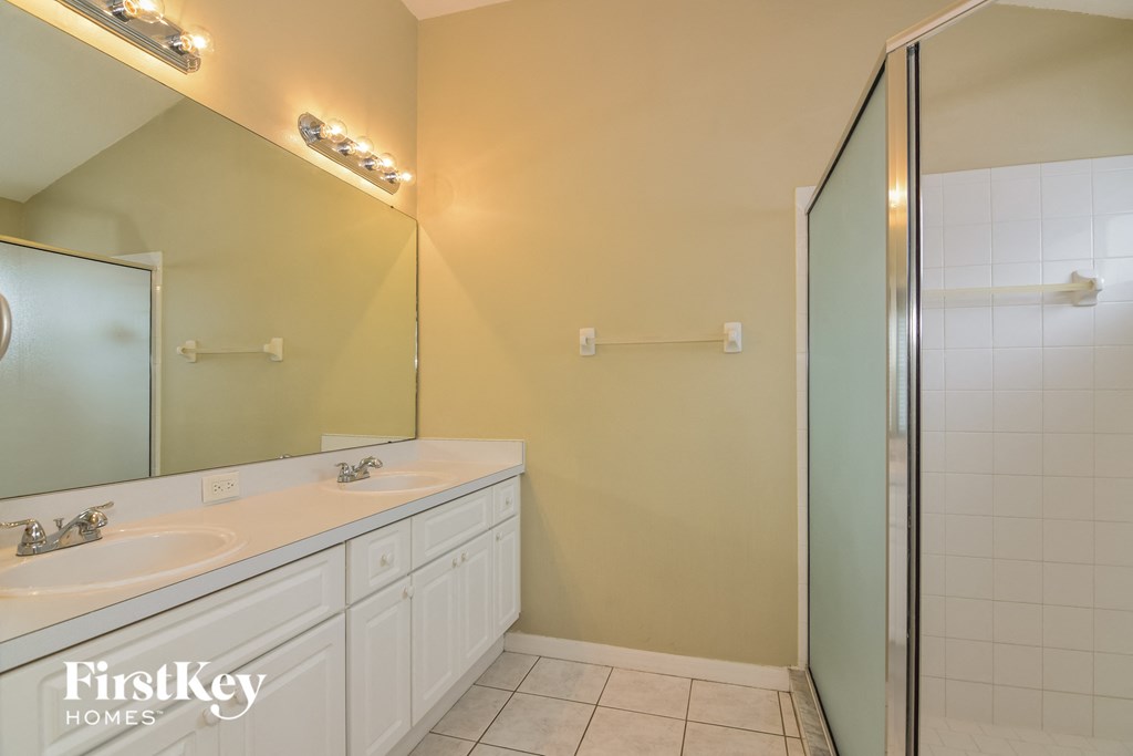 a white bathroom with two sinks and a shower