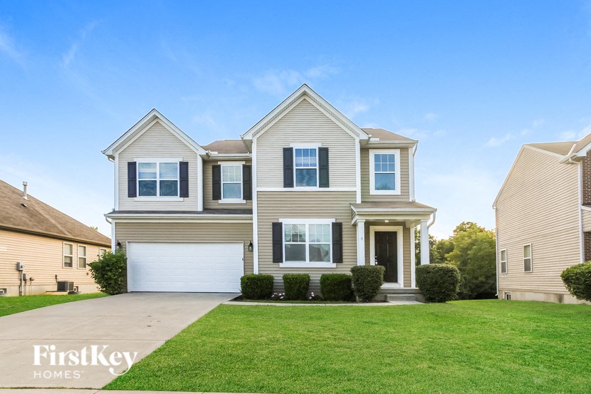 A large, two-story house with a garage is showcased in the image.