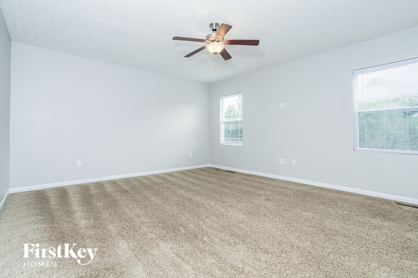 A spacious room with a ceiling fan and carpeted floor.