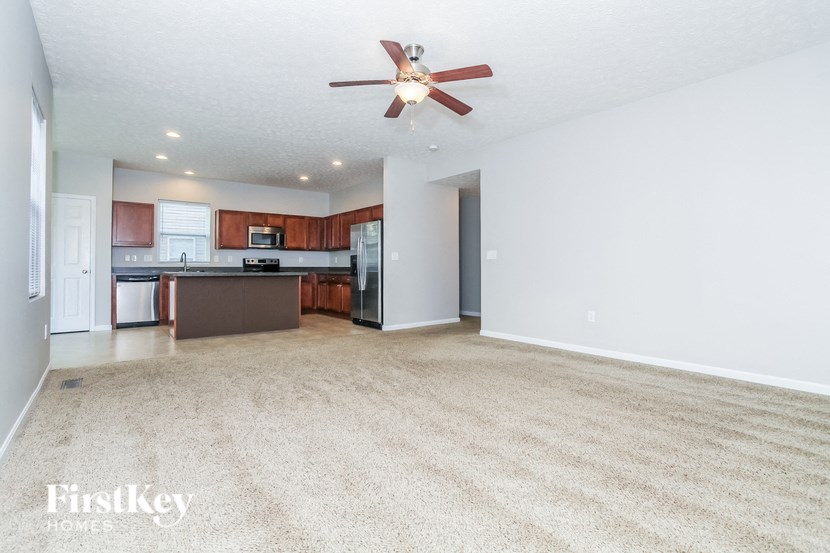 A spacious living room with a carpeted floor and a ceiling fan.