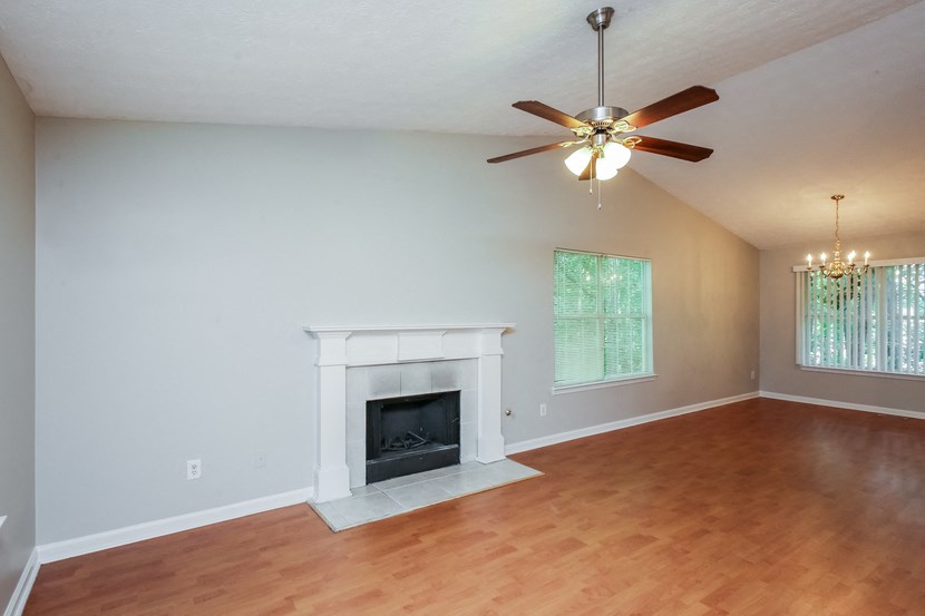 A living room with a fireplace and a ceiling fan.
