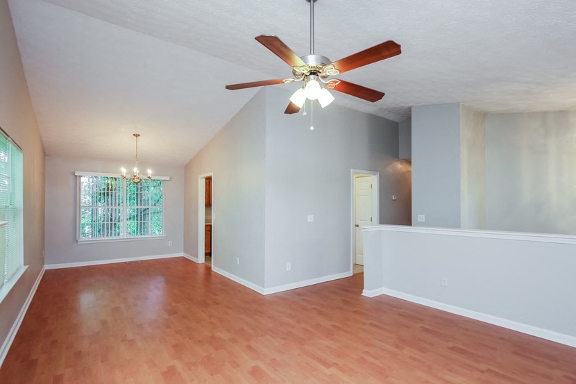 A room with a ceiling fan and wooden floors.