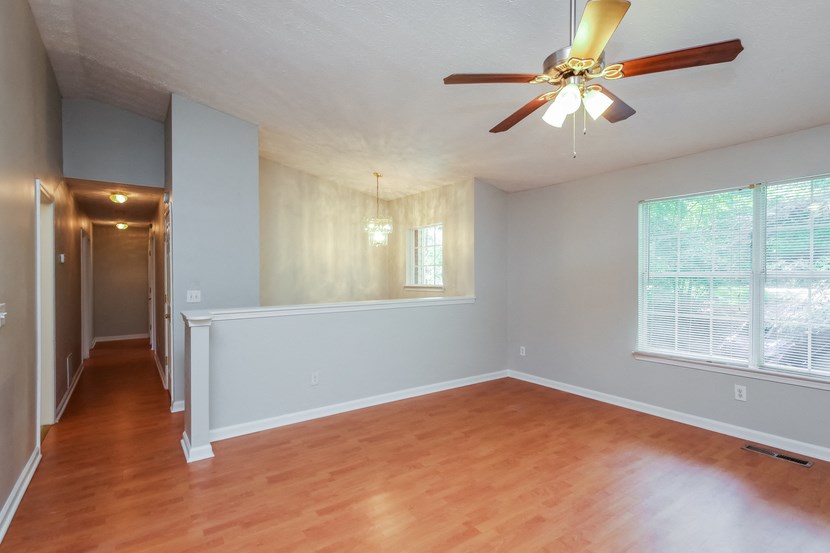 A room with a ceiling fan and wooden flooring.