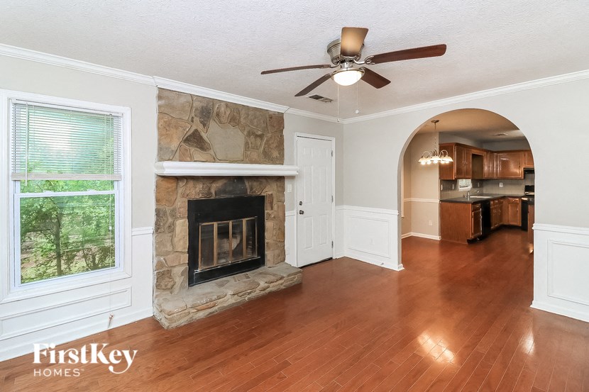 a living room with a stone fireplace and a ceiling fan