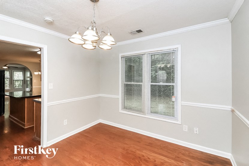 an empty dining room with a large window and wood flooring