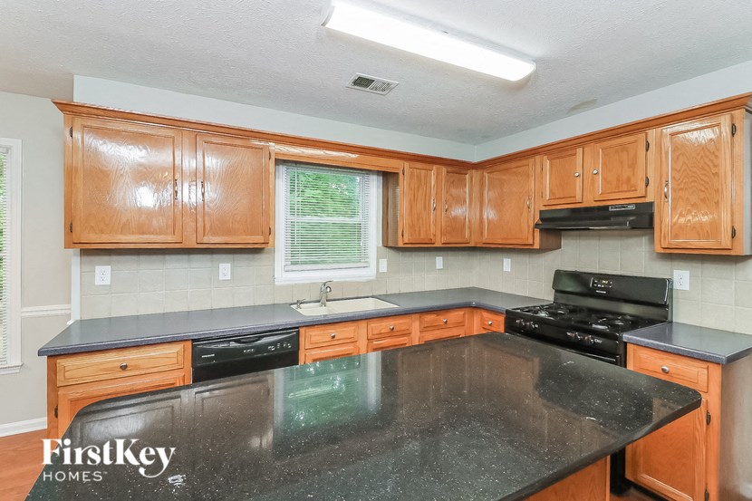 a kitchen with wooden cabinets and a black counter top