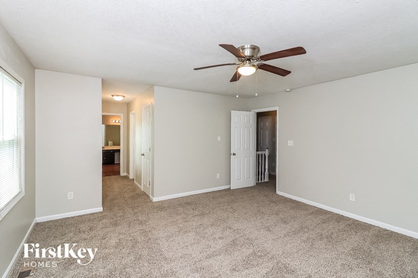 a living room with carpet and a ceiling fan