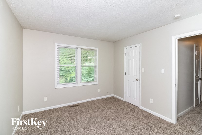 a bedroom with carpet and a white door and window