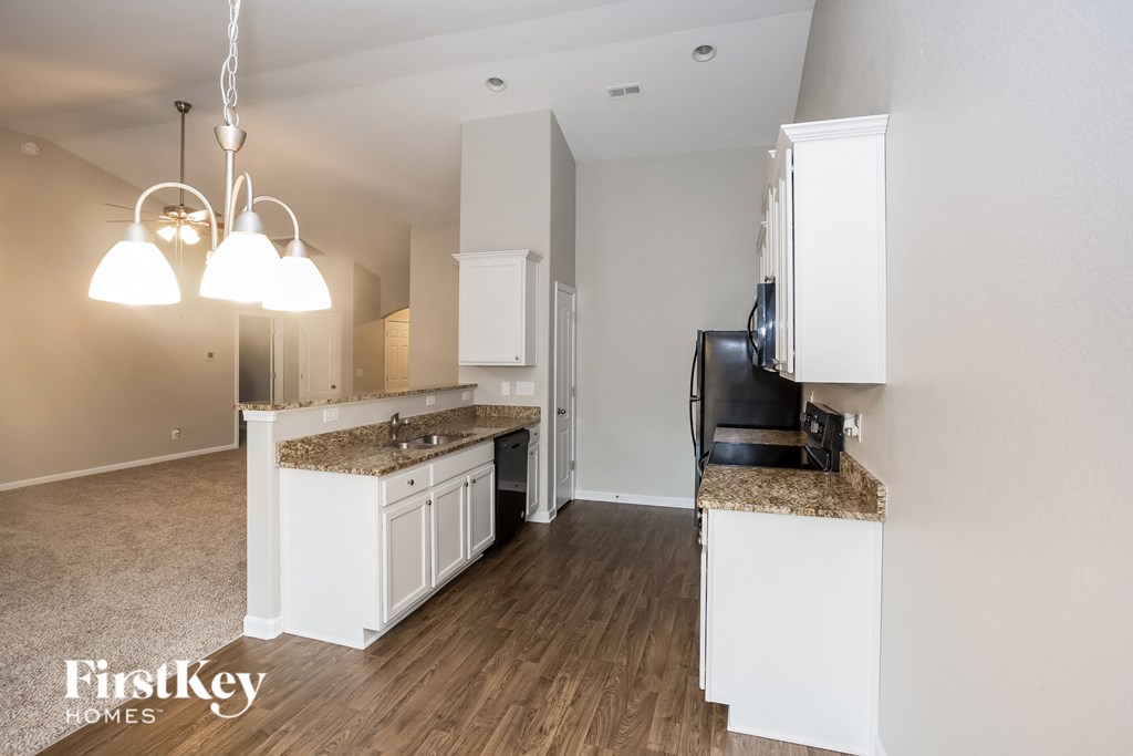 a kitchen with white cabinets and a counter top and a refrigerator
