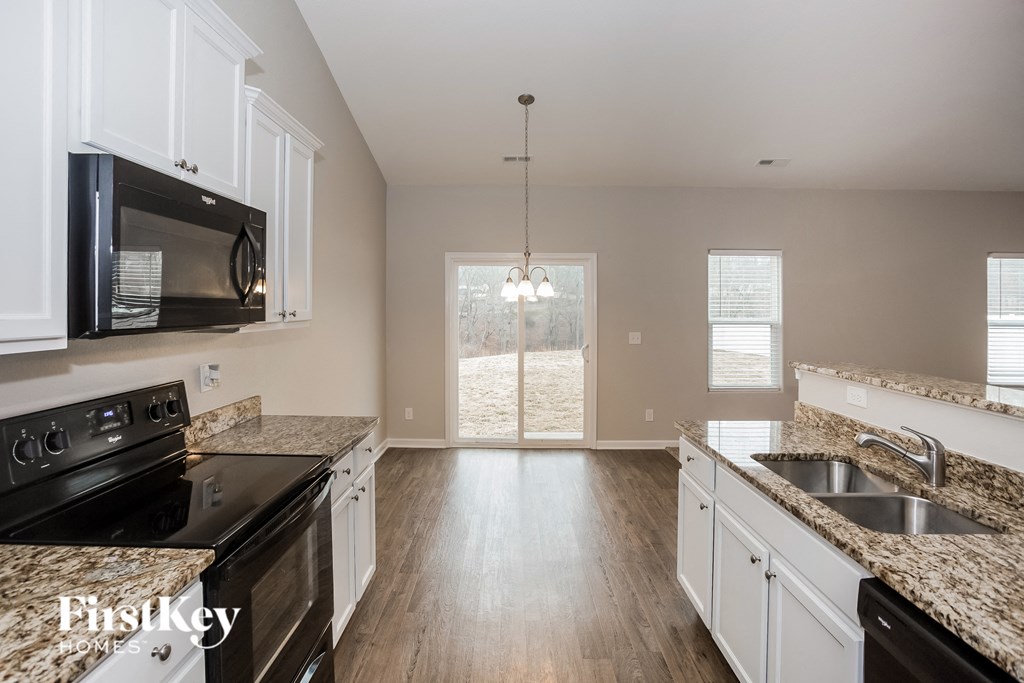 an empty kitchen with granite counter tops and black appliances