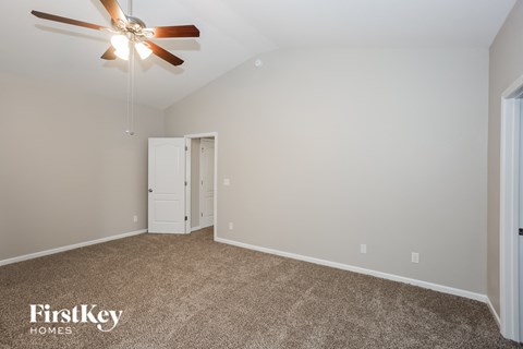 the spacious living room with ceiling fan and carpet