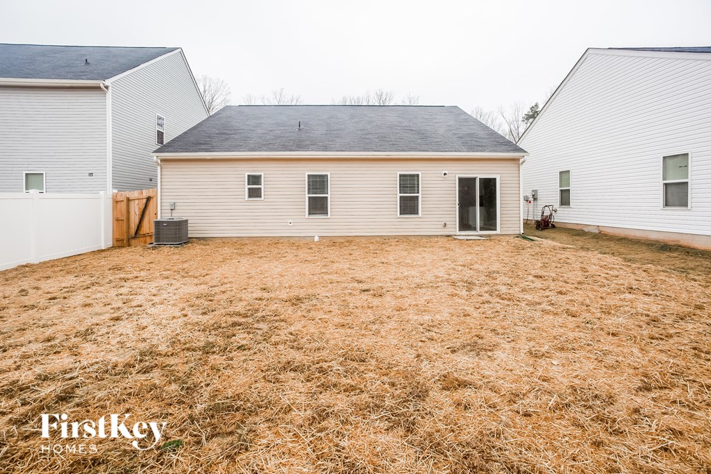 a backyard with a white house and a yard with brown grass