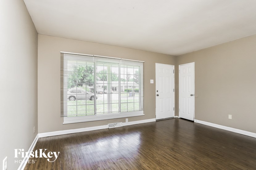 A room with wooden floors and a large window with blinds.