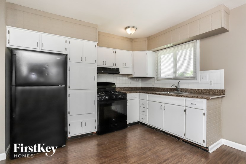 A kitchen with a black fridge and white cabinets.
