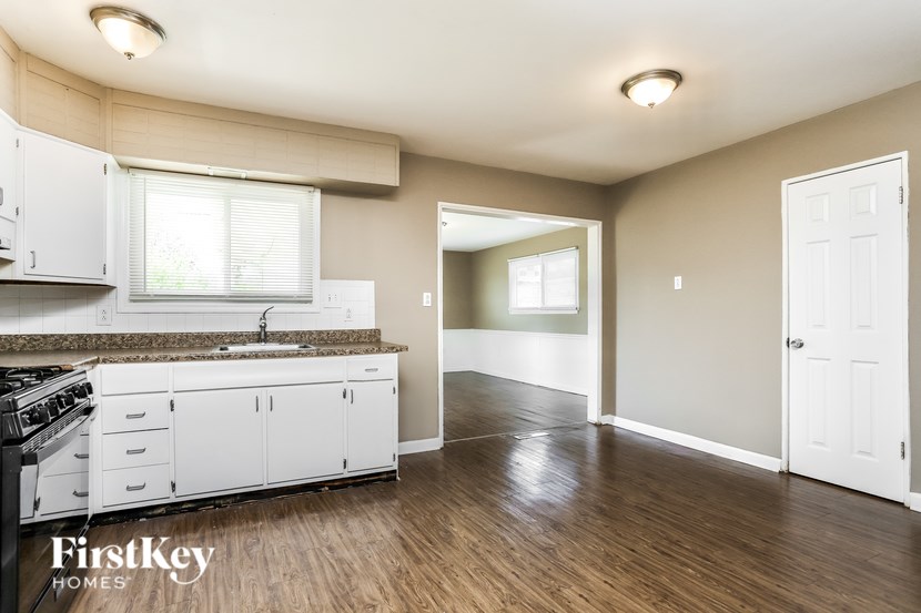 A kitchen with white cabinets and a wooden floor.