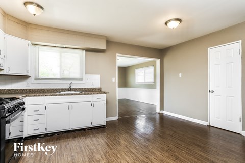 A kitchen with white cabinets and a wooden floor.