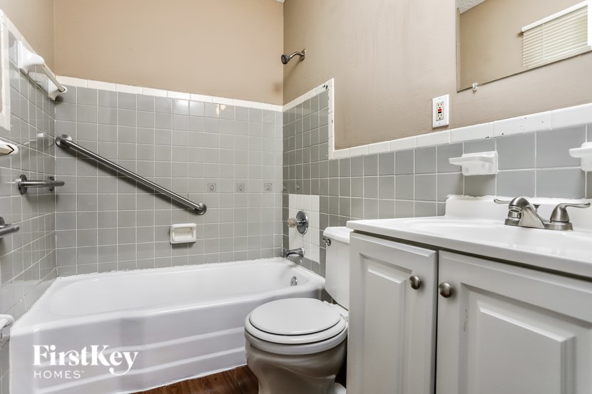 A white toilet sits next to a white bathtub in a bathroom.