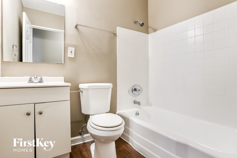 A white toilet sits next to a white bathtub in a bathroom.