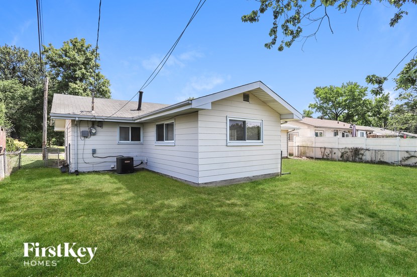 A small white house with a green lawn in front of it.