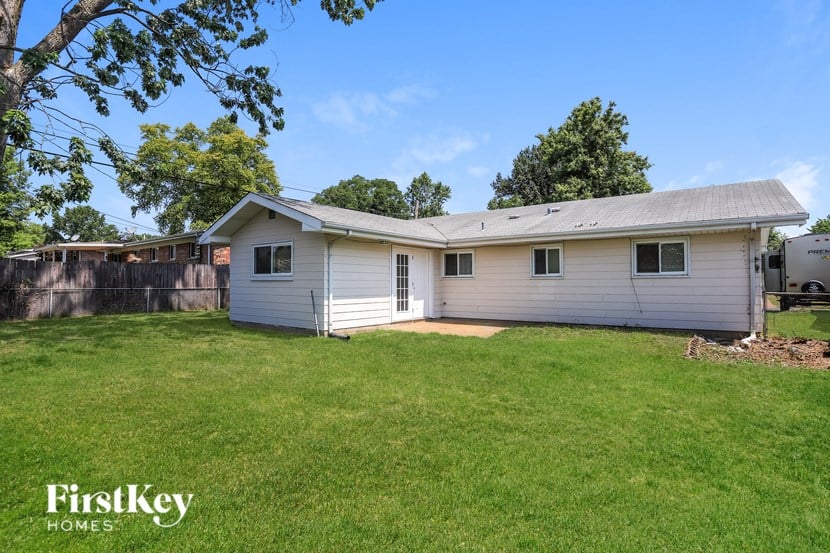 A small house with a garage is surrounded by a grassy yard.