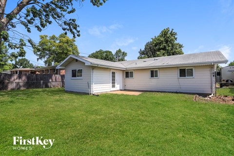 A small house with a garage is surrounded by a grassy yard.