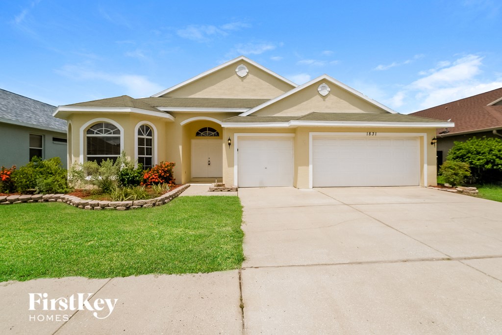 a yellow house with a driveway and a garage door