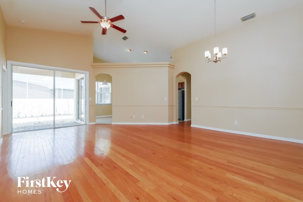 an empty living room with wood floors and a ceiling fan