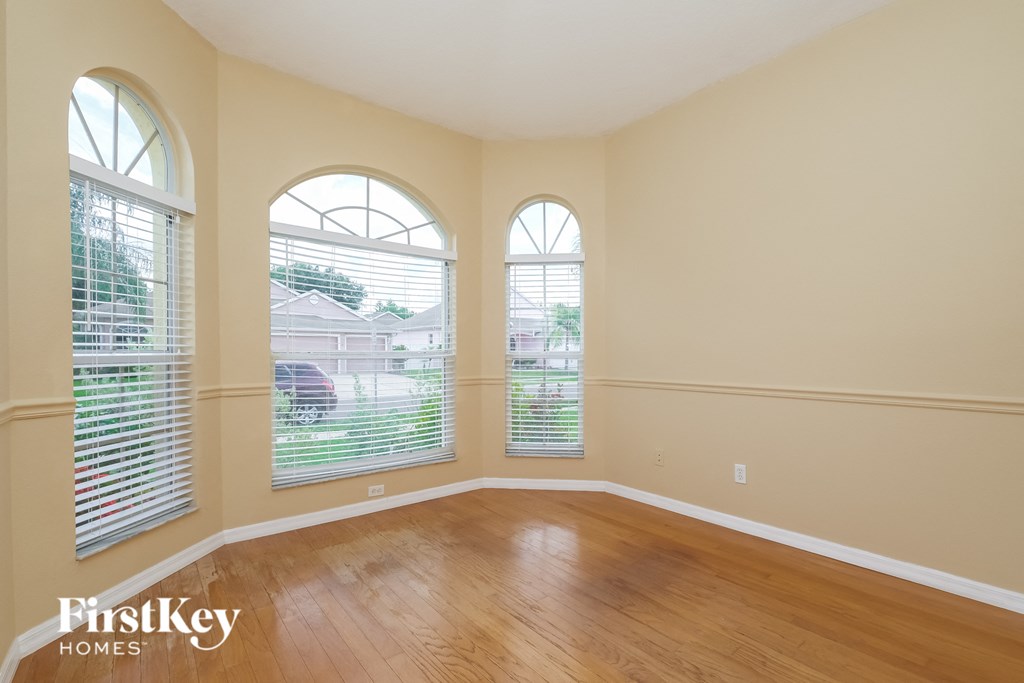 an empty living room with three windows and wood floors
