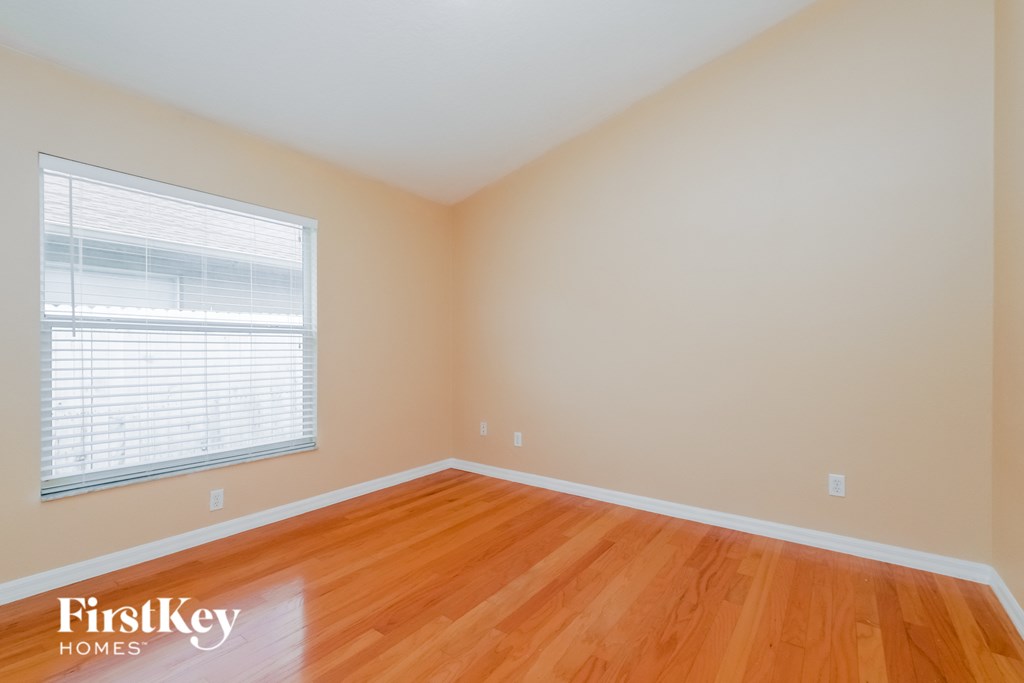 a bedroom with wood floors and a large window