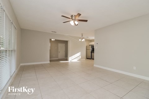an empty living room with a ceiling fan and tiled floor