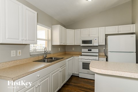 A kitchen with white cabinets and appliances.