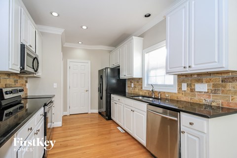 a kitchen with white cabinets and black counter tops and a black refrigerator