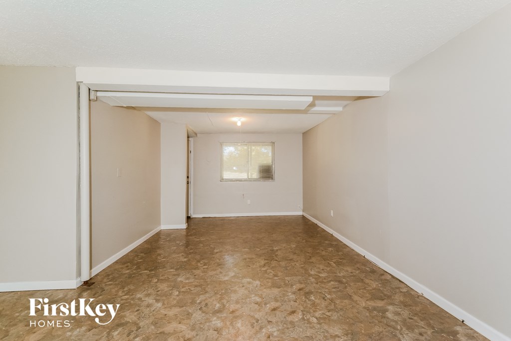 a living room with a carpeted floor and white walls and a window